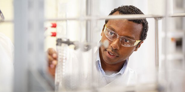 Ein Wissenschaftler im Labor trägt Schutzbrille und arbeitet konzentriert an einem Versuchsaufbau.