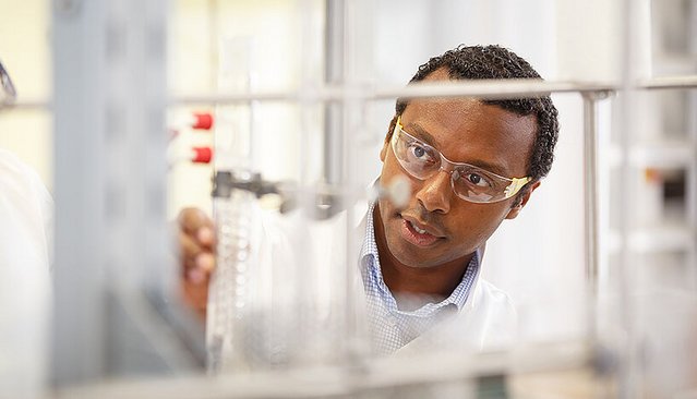 Ein Wissenschaftler im Labor trägt Schutzbrille und arbeitet konzentriert an einem Versuchsaufbau.