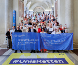 Gruppenbild mit dem Rektor der Universität Wien und ca. 50 Personen mit zwei Transparenten mit der Aufschrift "Zukunft lässt sich nicht einsparren".