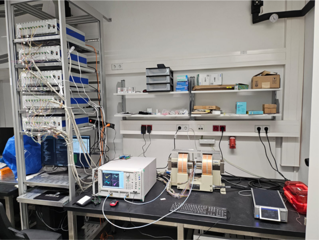 Experimental inverse-design setup consisting of the device itself, mounted between the pole shoes of an electromagnet, vector network analyzer (VNA), the five multi-channel current sources, other components and a PC for running the algorithms required to solve the inverse problem.