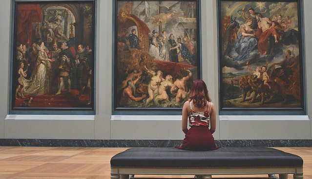 Woman in front of paintings.