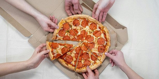 A couple of hands grabbing slices of Pizza.