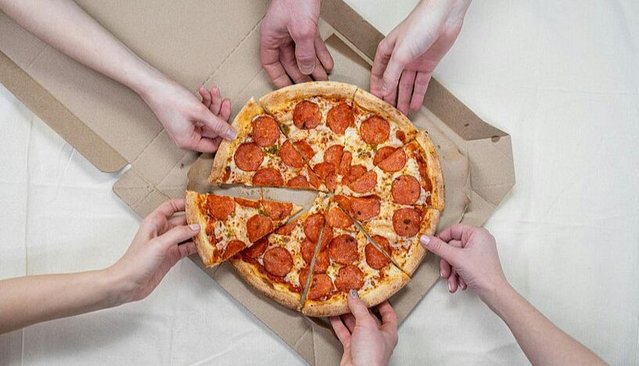 A couple of hands grabbing slices of Pizza.
